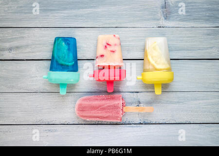 Varie ghiaccioli fatti in casa e dessert congelato su blu pallido sfondo di legno Foto Stock