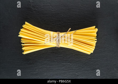 Materie spaghetti legato con una corda su uno sfondo nero, vista dall'alto Foto Stock