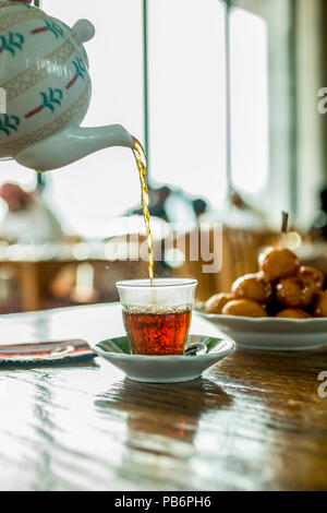 Orientale tè nero in vetro . Orientale il concetto di tè. Armudu coppa tradizionale, versando il tè nero alla tazza Foto Stock