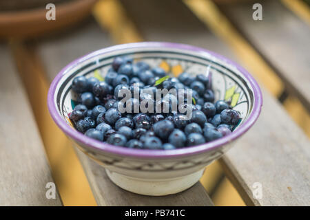 Mature mirtilli di bosco (mirtillo, whortleberry, blaeberry, huckleberry) in un recipiente a motivi geometrici. Close-up Foto Stock