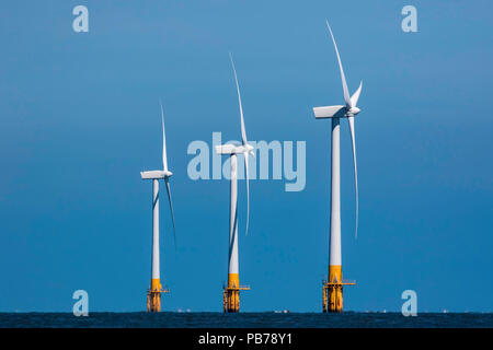 L'aumento di eco-energia eolica. Offshore di energia pulita wind farm. Tre sincronizzato wind turbine di potenza nel profilo di altezza crescente. Foto Stock