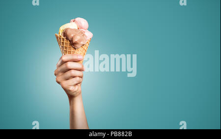 Mano che tiene un grande cono gelato Foto Stock