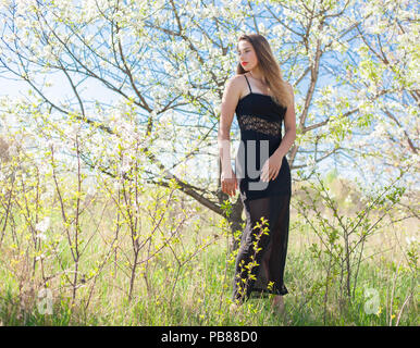 Bella ragazza in un abito di estate circondata da una struttura di fioritura Foto Stock