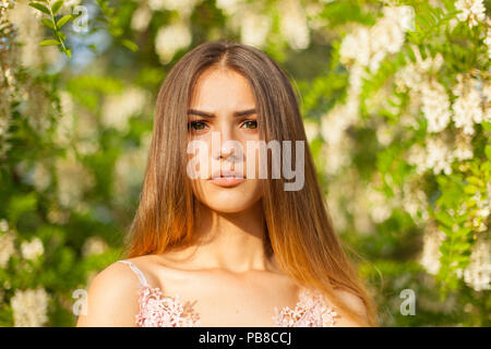 Close-up ritratto di una giovane e bella ragazza nel giro di acacia bianco in primavera Foto Stock