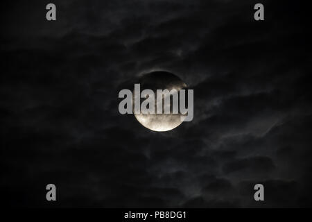 Luminosa luna piena contro le nuvole scure Foto Stock