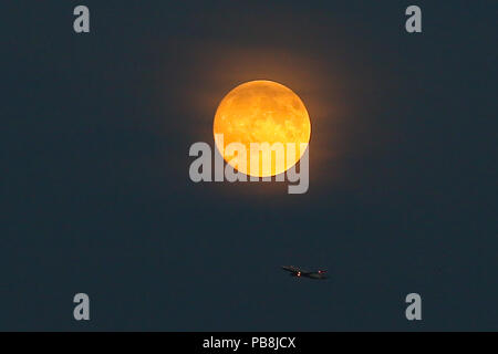 A nord di Londra. Londra. Regno Unito 26 luglio 2018 - A British Airways piano battenti sotto la luna di sangue nel nord di Londra, come il più lungo dell'eclisse lunare del secolo, fissata per venerdì 27 luglio 2018, ha già iniziato a girare il corpo celeste di un profondo colore scarlatto. La luna di sangue sarà il primo del Regno Unito, il possibilità di vedere un grande eclipse nel 2018, e secondo la NASA Luna esperti presso il Goddard Space Center, l'eclipse durerà circa un ora e 43 minuti. Credito: Dinendra Haria/Alamy Live News Foto Stock