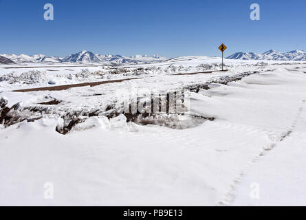 Coperte di neve strada attraverso il deserto di Atacama con cartello stradale nella parte anteriore delle Ande, Altiplano, Bolivia Foto Stock