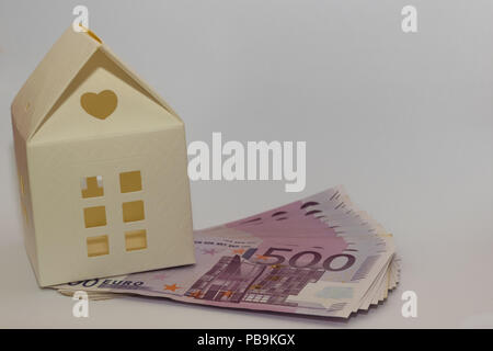 Modello in carta casa giocattolo sulla parte superiore di 500 banconote in euro. Immagine concettuale di acquisto, vendita, il salvataggio, il prestito per una casa. Foto Stock