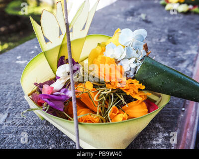 Canang Balinese sari offerta con fiori arancione e un Incenso stick, Tempio Besakih Bali, Indonesia Foto Stock