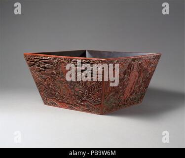 Misura di riso con quattro divinità di costellazione. Cultura: la Cina. Dimensioni: H. 6 1/2 in. (16,5 cm); W. 12 3/4 in. (32,4 cm); D. 12 7/8 in. (32,7 cm). Data: XVI secolo. Questo recipiente di forma e motivo lo identifica come un raro esempio di una misura di riso utilizzato nel pensiero daoista rituali. Su ogni lato è una figura in un pensiero daoista accappatoio con uno dei quattro animali (dragon, bue, cane e capra). Questi animali rappresentano divinità di costellazione dal set di ventotto mansions in astronomia cinese, che riflettono il movimento della luna in un mese siderale. Museo: Metropolitan Museum of Art di New York, Stati Uniti d'America. Foto Stock