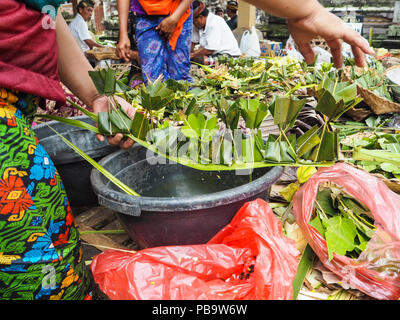 Le donne la creazione di delicati palm lasciare offerte per Nyepi Bali Foto Stock