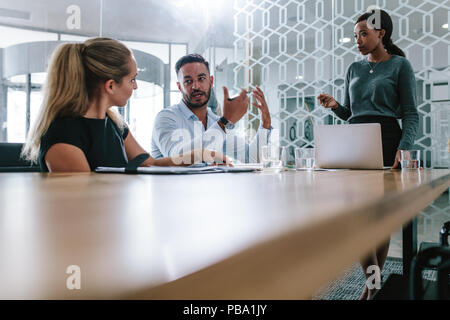 Giovane uomo condividendo le sue opinioni con i colleghi di lavoro nella sala riunioni durante la riunione di affari. Team di Professionisti avente una nuova riunione di progetto in sala conferenze Foto Stock