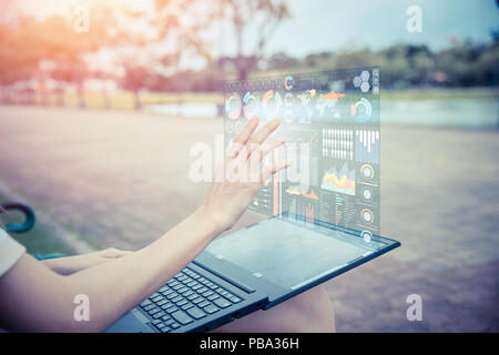 Imprenditrice mano utilizzando la tecnologia avanzata di ologramma del calcolatore air display di schermo di proiezione informazioni aziendali grafico di dati esterna per il supporto decisionale Foto Stock