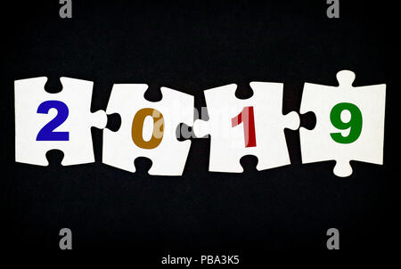 Quattro pezzi di un puzzle con i numeri 2019 su sfondo nero. Close-up. Foto Stock