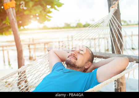 Tempo per la pigrizia. L'uomo si trova in una amaca e gode di tutto il resto. Foto Stock