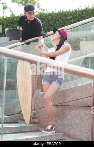 Allegro giovani cinesi giovane con lo skateboard acqua potabile su scale Foto Stock