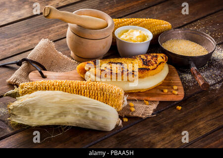 Tipica cucina Venezuelana, vista dall'alto di un tavolo di legno con diversi ingredienti per la preparazione di Cachapas con formaggio, mais, burro, grano macinato Foto Stock