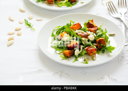 Fresca insalata di autunno con la zucca cotta al forno, rucola, formaggio e semi sul tavolo bianco panno. Spazio per la copia Foto Stock