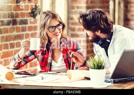Due architetti ambiziosi discutendo nel progetto di costruzione loft ufficio moderno, essi e sorridente con notebook Foto Stock