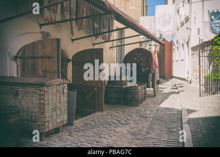 Stilizzata strada medievale con un carrello e botti di rovere sotto le norme sulle pareti a Riga Foto Stock