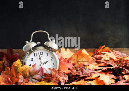 Sveglia in colorate Foglie di autunno contro uno sfondo scuro con profondità di campo ridotta. Ora legale del concetto. Foto Stock