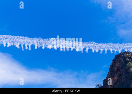 Il vapore sentiero a sinistra da un piano che passa in un cielo blu Foto Stock