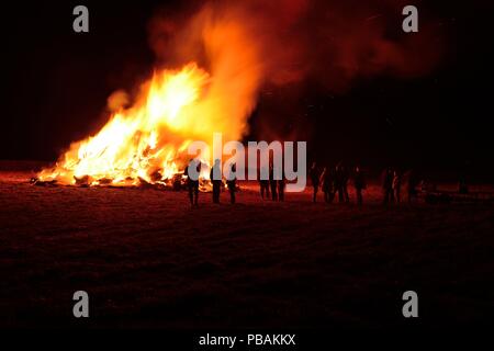 Foto di un gruppo di persone in piedi intorno a un falò sulla notte dei falò Foto Stock