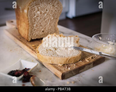 In cucina, sul pane tagliere abbiamo una fetta di pane e burro di alcune unità di sollevamento su di esso e alcune jam è anche disponibile. Foto Stock