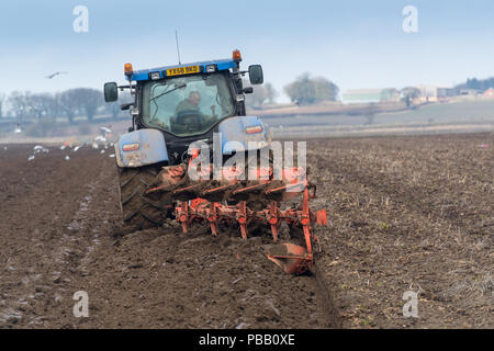 L'aratura di un campo con una New Holland T7030 e un solco 5 reversibile aratro Kuhn, voce di distanza. North Yorkshire, Regno Unito. Foto Stock