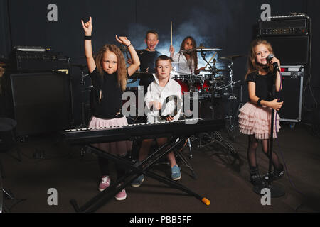 Dei bambini felici di cantare e suonare la musica in studio Foto Stock