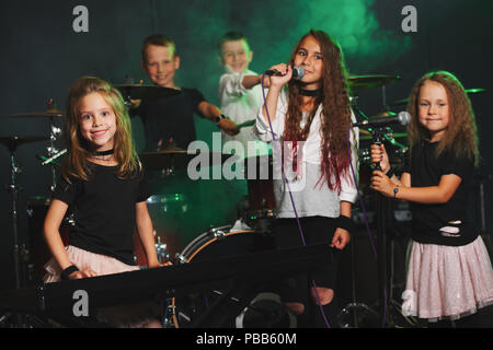 Dei bambini felici di cantare e suonare la musica in studio Foto Stock