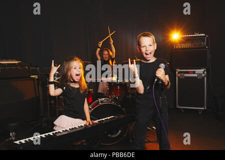 Dei bambini felici di cantare e suonare la musica in studio Foto Stock