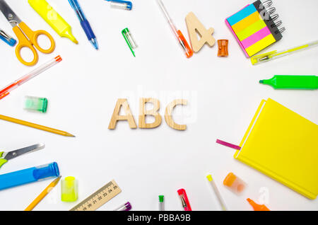 Lettere A, B, C sul banco di scuola. concetto di istruzione. torna a scuola. articoli di cancelleria. Sfondo bianco. adesivi colorati, penne, matite, forbici. vie Foto Stock