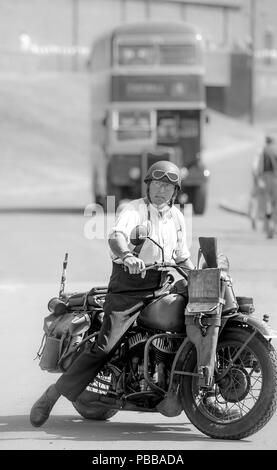 Bianco & Nero, ritratto di costume re-enactor sul fermo motocicletta vintage, Black Country Museum 1940s WWII evento; bus vintage in background. Foto Stock