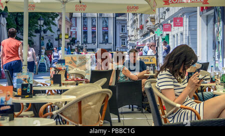 Zemun, Belgrado, Serbia, Maggio 2018 - Gli ospiti su un cafe bar terrazza ossessivamente in impegno con il loro smartphone non avente alcun riguardo per le loro frazioni Foto Stock