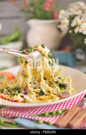 La pasta italiana, con fresco verde di piselli e formaggio, su uno sfondo di fiori. Foto Stock