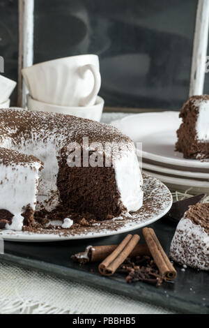 Il cioccolato Devil's Food Cake con glassa di marshmallow. Dessert fatti in casa closeup view, spolverata di cacao in polvere. Foto Stock