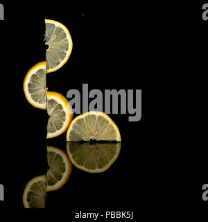 Equilibrato in modo creativo di limone fresco fette di frutta su sfondo scuro. Foto insolite. Sembrano sfidare la forza di gravità. Isolato su nero Foto Stock