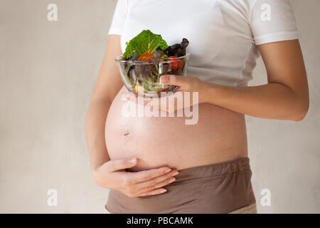 Donna incinta il ventre e insalata di verdure. Alimentazione sana. Foto Stock