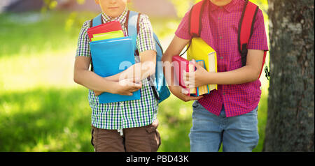 I bambini con zaini in piedi nel parco vicino alla scuola Foto Stock