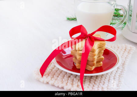 Biscotti a forma di stelle e latte per Santa Claus su sfondo bianco Foto Stock