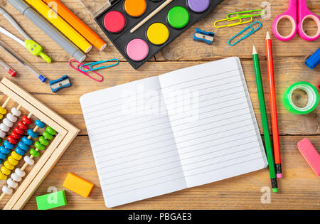 Si torna a scuola concetto. Forniture scolastiche e notebook in bianco su sfondo di legno, lo spazio per il testo, la vista superiore Foto Stock
