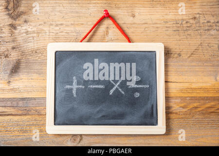 Concetto di matematica. I simboli matematici sulla lavagna con telaio in legno, sullo sfondo della parete Foto Stock