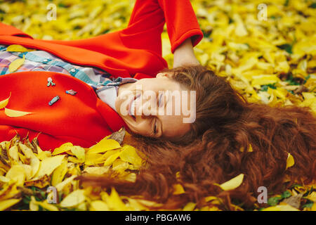 Giovane bella signora circondato Foglie di autunno Foto Stock