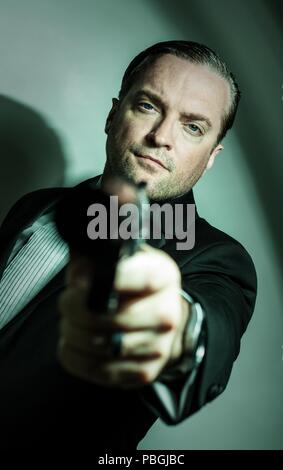 Ritratto di un uomo bello in possesso di una pistola Foto Stock