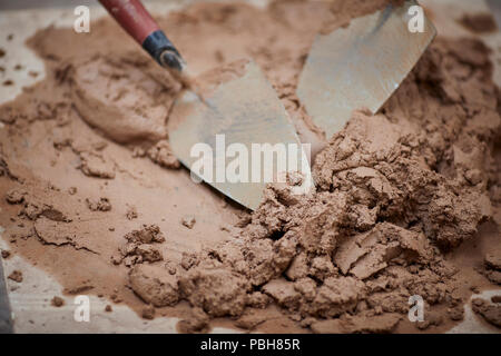 Gli strumenti del mestiere per i costruttori, muratori, homebuilders. una cazzuola in un impasto di cemento e sabbia mix di malta Foto Stock