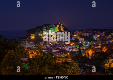 Vista aerea della pittoresca cittadina costiera di Parga illuminata di notte. Centrato lo storico castello veneziano di Parga Epiro, Grecia, Europa Foto Stock