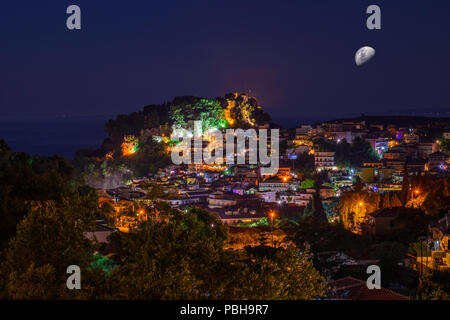 Vista aerea della pittoresca cittadina costiera di Parga illuminata di notte. Centrato lo storico castello veneziano di Parga Epiro, Grecia, Europa Foto Stock