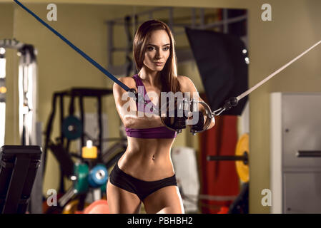 Giovane donna fitness in palestra eseguire esercizio con cavo crossover, macchina la foto in orizzontale Foto Stock