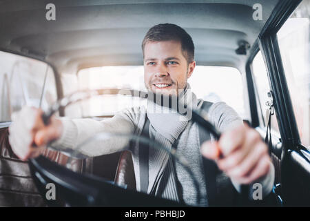 Bel uomo seduto dentro la sua vecchia auto d'epoca Foto Stock